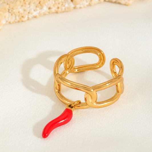 Gold ring with a red chilli charm on a light background