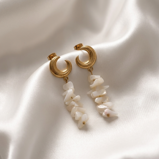 Gold hoop earrings with white stones on a white fabric background