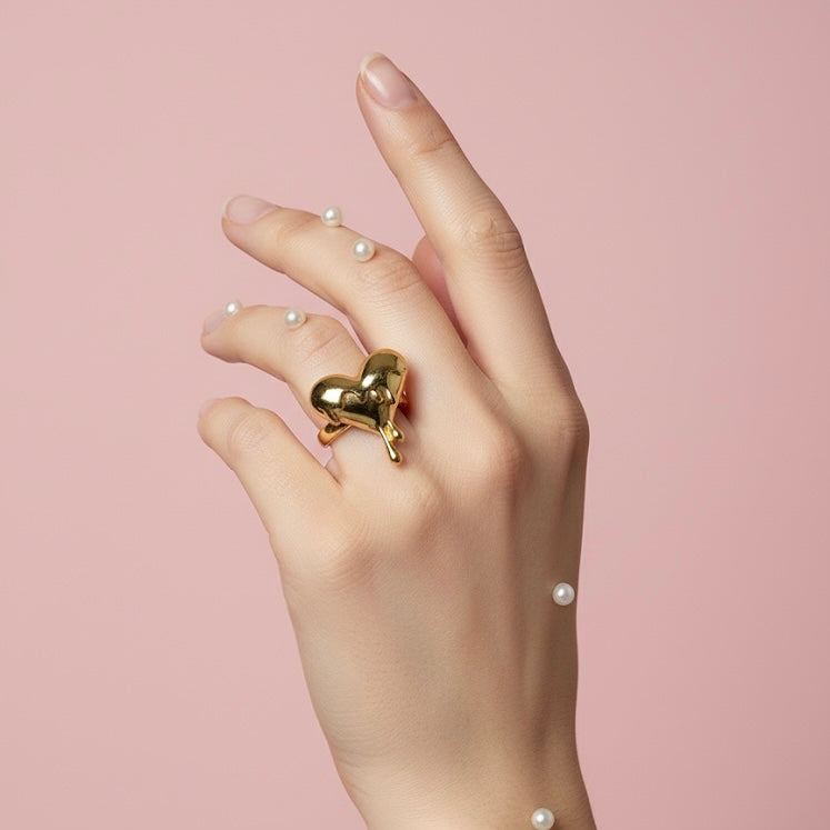 Hand wearing a gold heart-shaped ring