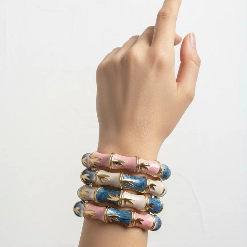 Hand wearing multiple colorful bracelets on a light gray background